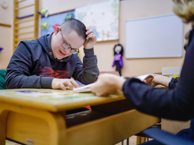 Boy with disability sitting at desk in school setting. 